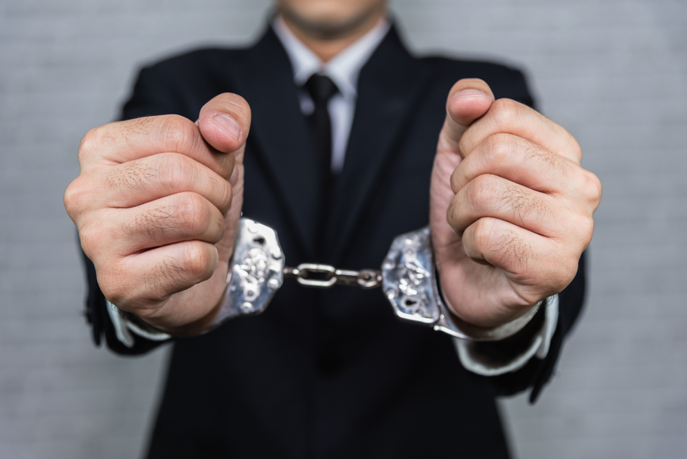 businessman in handcuffs arrested isolated on gray background
