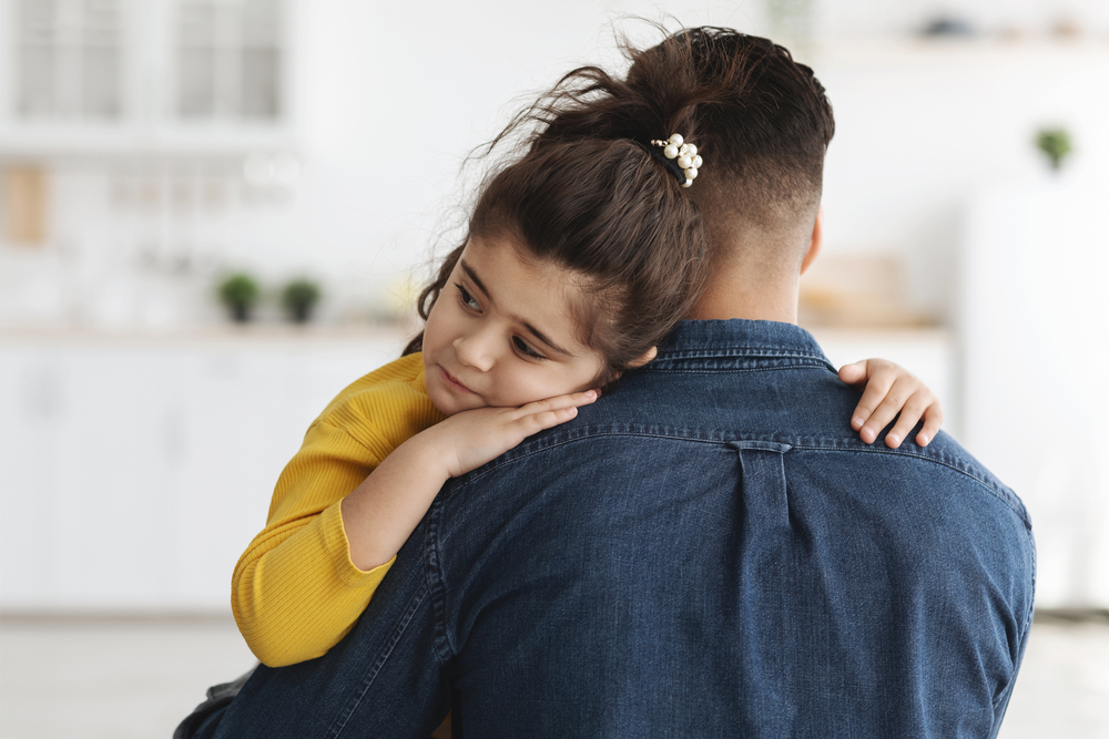 caring dad comforting upset little arab daughter at home