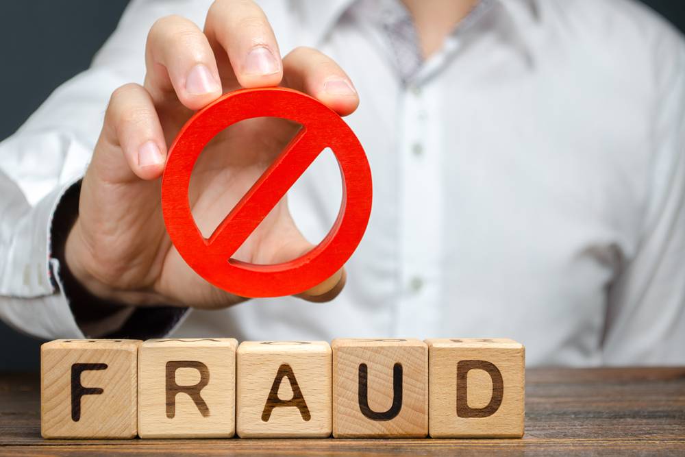 A man holds a red NO prohibition symbol over word fraud